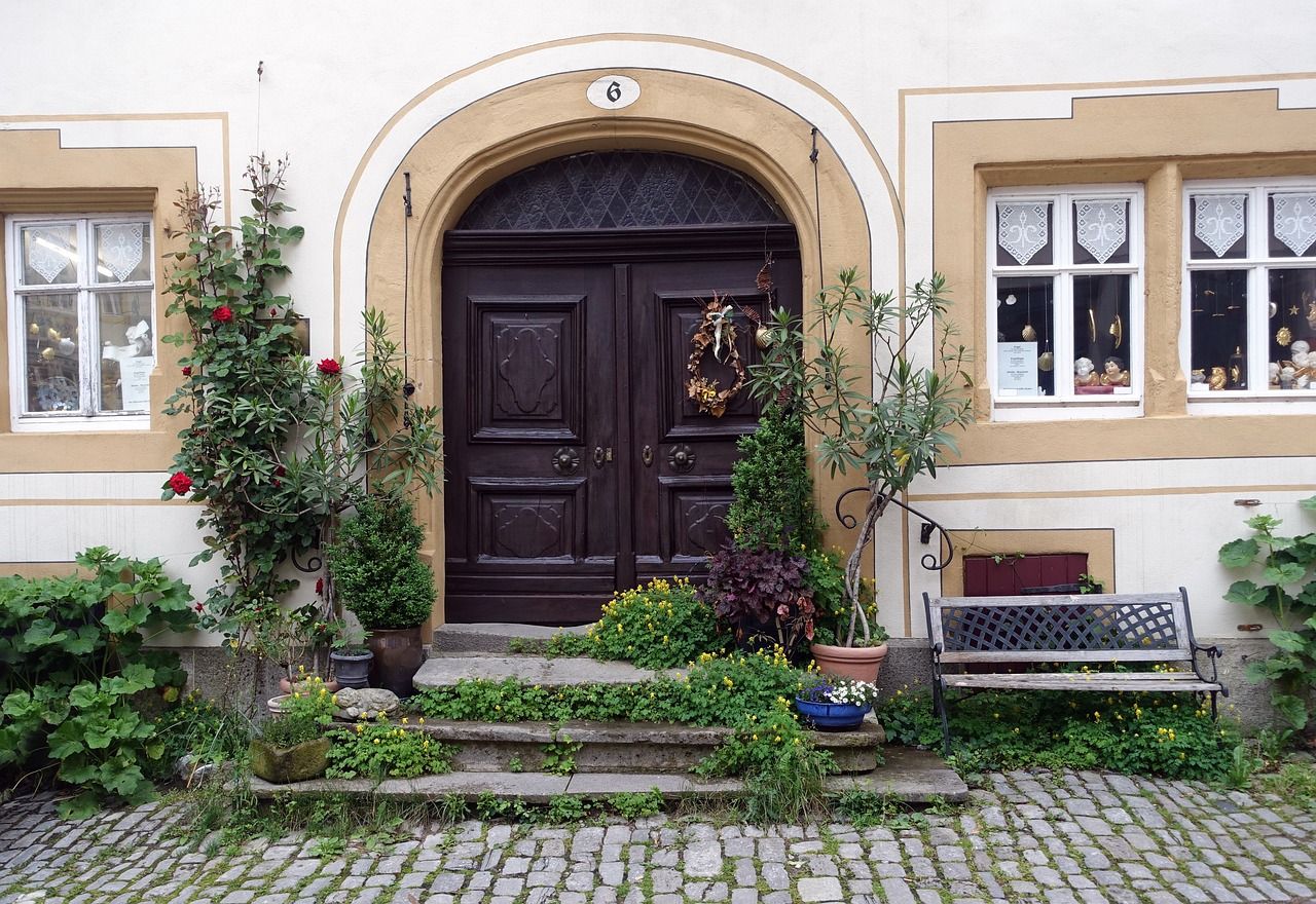 Entrée de maison fleurie avec plantes en pot et banc